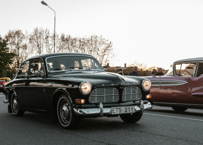 Ein schwarzer Classic-Car fährt auf einer Straße, umgeben von anderen Autos.