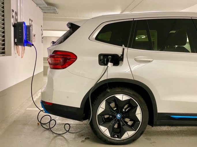 Ein weißer BMW SUV wird an einer Ladestation aufgeladen.